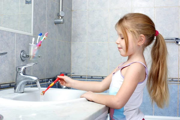 Petite fille avec brosse à dents dans la salle de bain — Photo