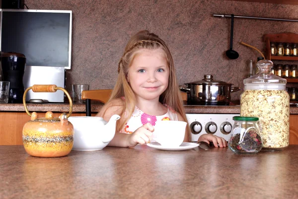 Malá dívka snídaně s šálkem horkého nápoje v kuchyni — Stock fotografie