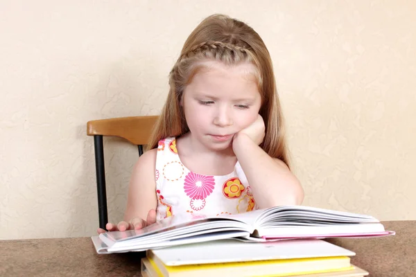 Küçük kız evde sarı duvara karşı kitap okuyor. — Stok fotoğraf