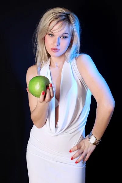 Flicka med grönt äpple under blått ljus mot svart bakgrund — Stockfoto