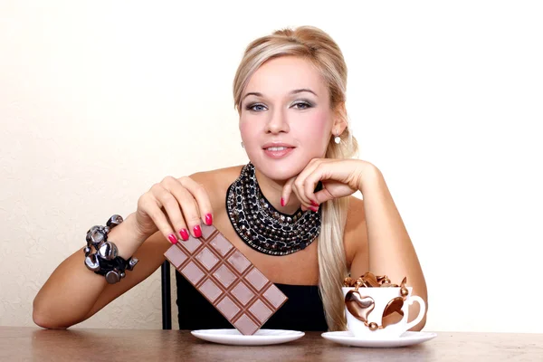 Woman with cup of chocolate against yellow wall at table — Stock Photo, Image