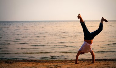 Man doing handstand on beach clipart