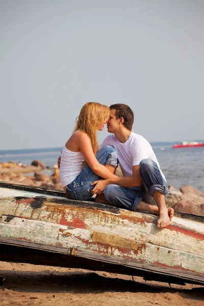 Пара сидящих на старой лодке и целующихся — стоковое фото