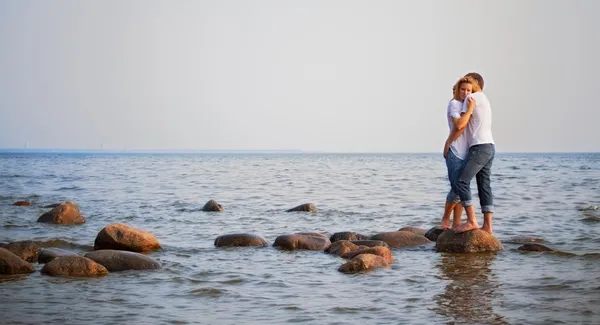 stock image Couple embrace on a stone in sea