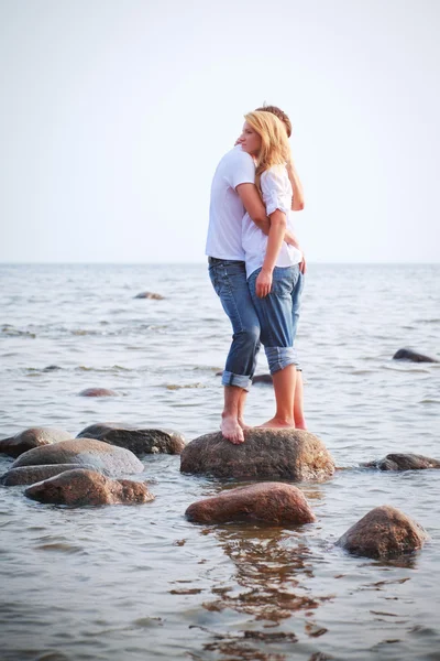 Пара обнимает камень в море — стоковое фото