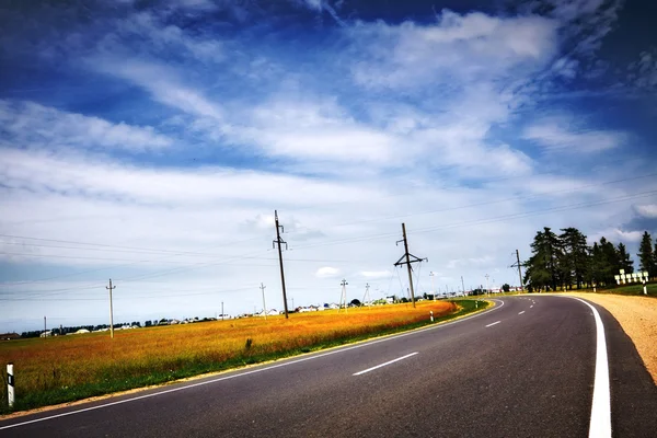 Autostrada sotto cielo nuvoloso blu — Foto Stock