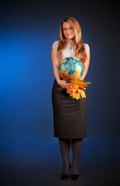 Гарненька вчителька з глобусом і кленовим листям — стокове фото