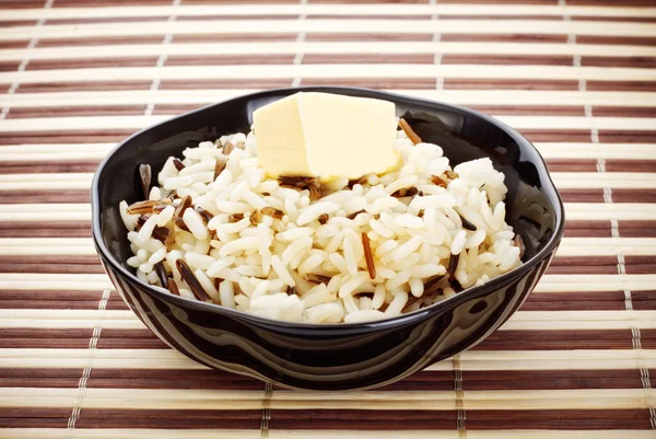 stock image Black bowl with cooked rice and butter on bamboo napkin