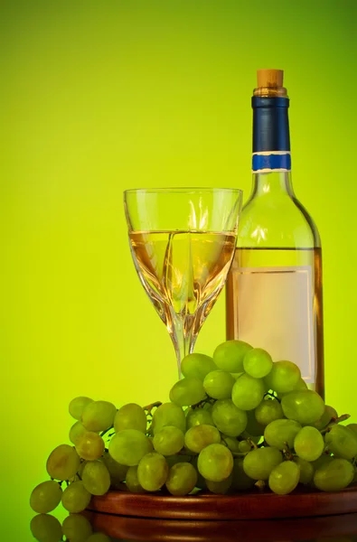 stock image Bottle and glass of wine, grape bunch, green background