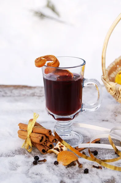 一个玻璃杯子装满热温热的红酒 橘子皮和上白雪皑皑的表 垂直的香料 图库图片