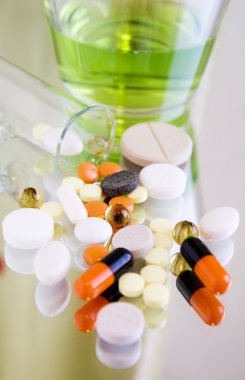 Different colorful pills and medicines on a mirror surface, close up, blur background clipart