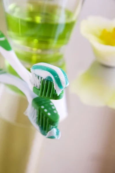 Munhygien produkter på en spegel yta - tandborste med tandkräm Stockbild