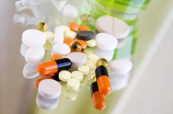 Diferentes píldoras de colores y medicamentos en una superficie de espejo Imagen De Stock