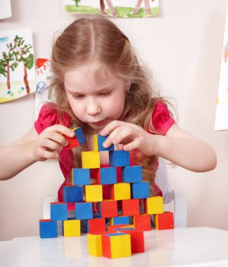 Child preschooler play wood block in play room. clipart