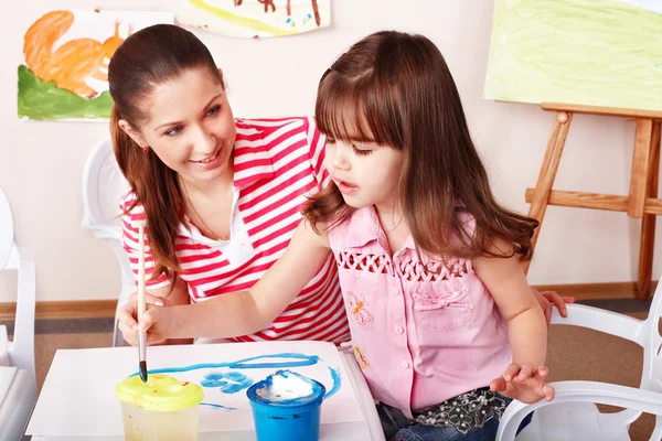 Ребенок с учителем рисует краски в игровой комнате . — стоковое фото