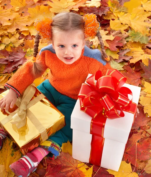 Dítě v pomerančové listí a krabičky. — Stock fotografie