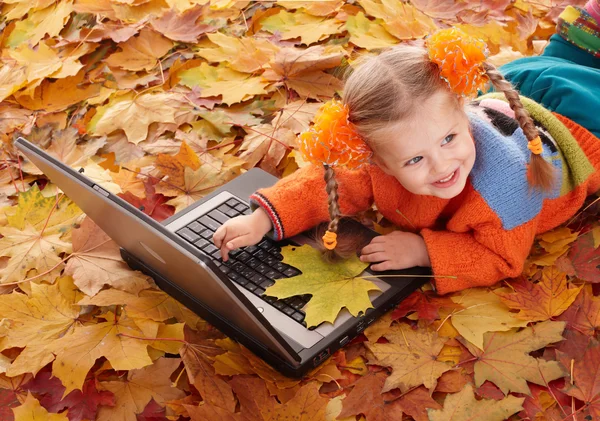 Child in autumn orange leaves with laptop. — Stock Photo, Image