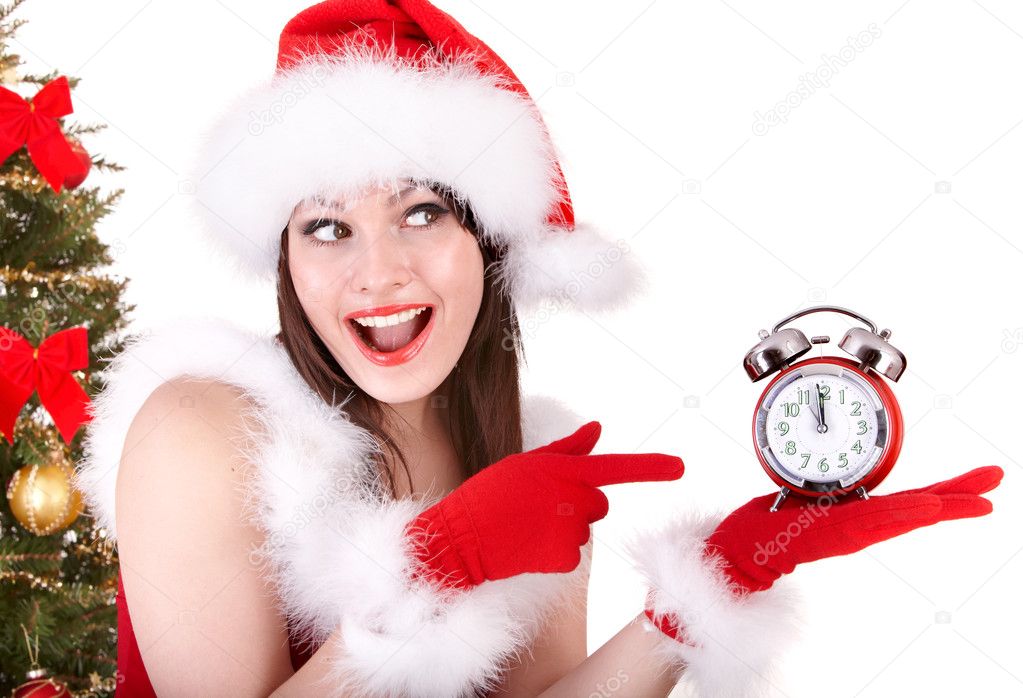 Christmas girl in santa hat and fir tree with alarm clock.