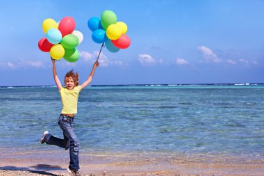 Balonlar ile plajda oynayan çocuk