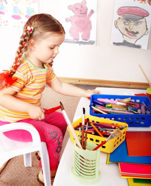 Child prescooler with pencil in play room. clipart