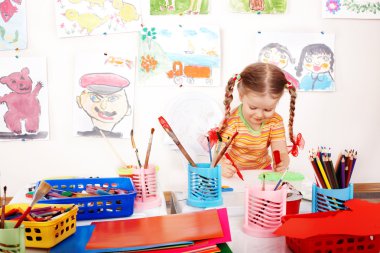 Child with colour pencil in play room. clipart