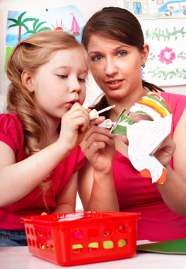 Child with teacher in play room. clipart