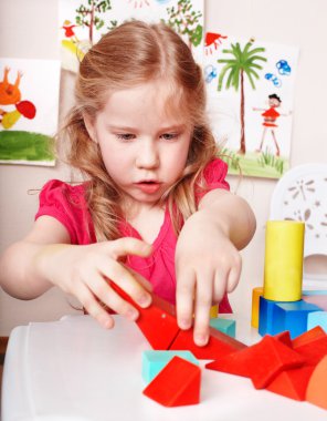 Child preschooler play wood block in play room. clipart