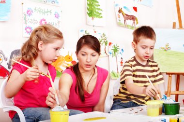 Children with teacher draw paints in play room. clipart