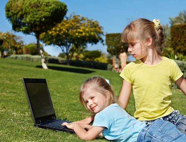 Kinder mit Laptop im grünen Gras. — Stockfoto