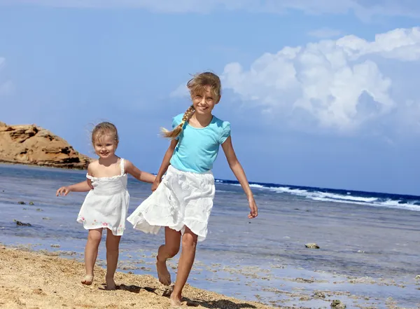 Des enfants se tenant la main marchant sur la plage . — Photo