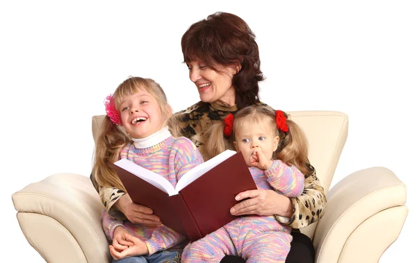 Mormor och två barnbarn läser bok. — Stockfoto