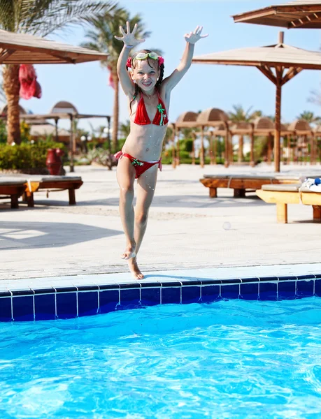 Ragazza con occhiali e costume da bagno rosso saltare in piscina . — Foto Stock