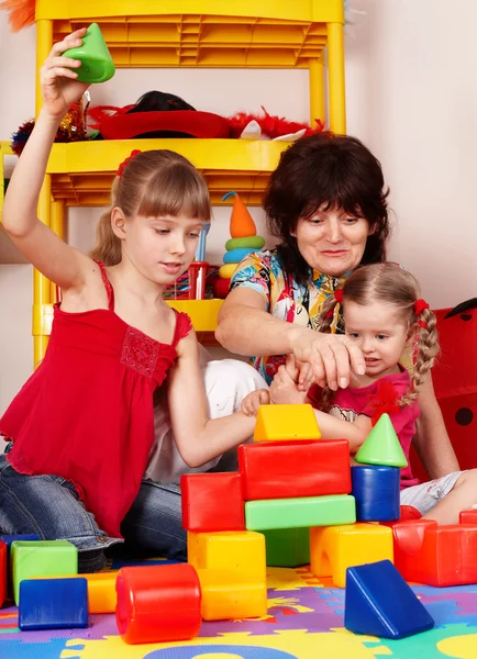 Kinder mit Block und Seniorin im Spielzimmer. — Stockfoto