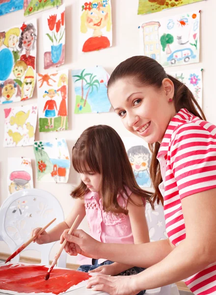 Kind schilderen met leraar in de kleuterschool. — Stockfoto