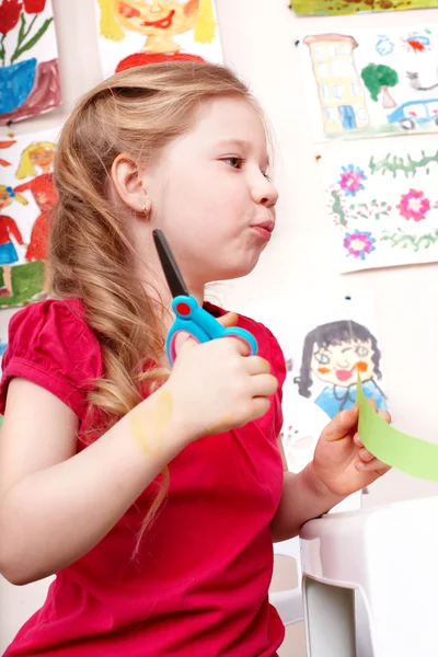 Child with scissors cut paper in play room. — Stock Photo, Image