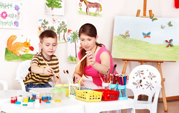 Niño con el maestro dibuja pinturas en la sala de juegos . —  Fotos de Stock