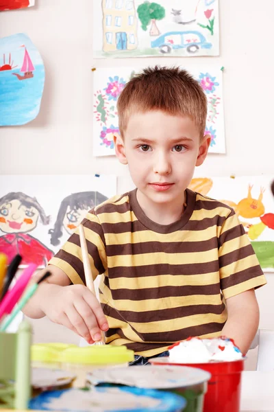 Bambino con foto e pennello in sala giochi . — Foto Stock