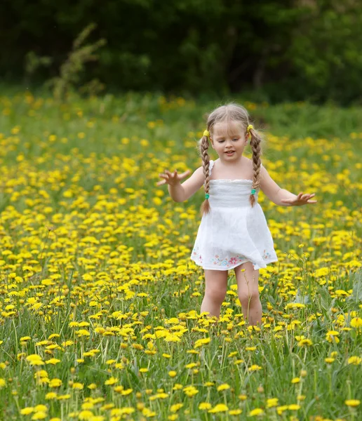 Liten flicka på gräset i blomma. — Stockfoto