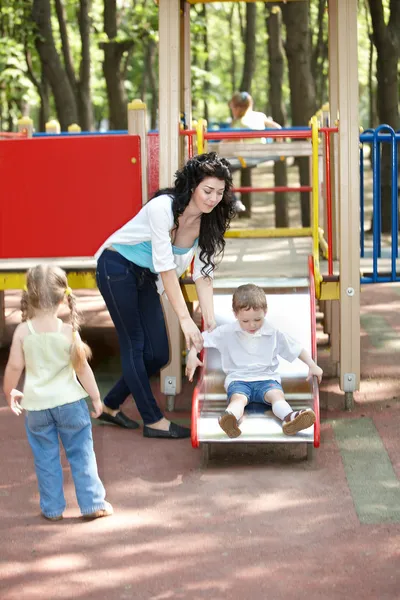 Mother with children on slide outdoor. — Stock Photo, Image