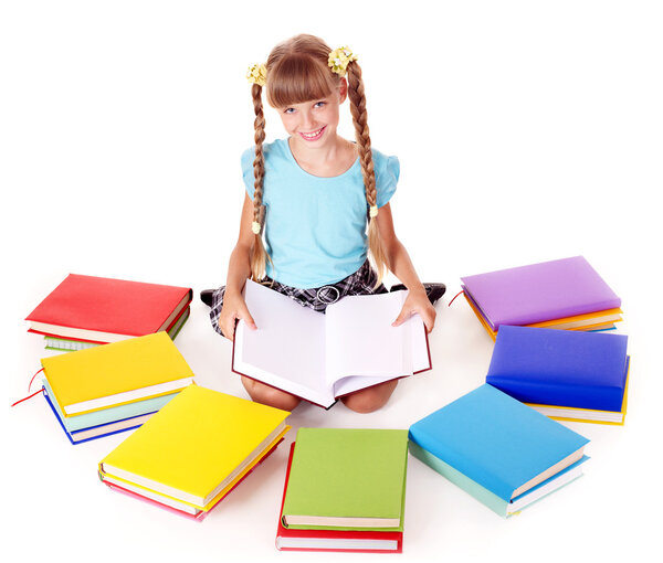 Child with pile of books reading on floor.