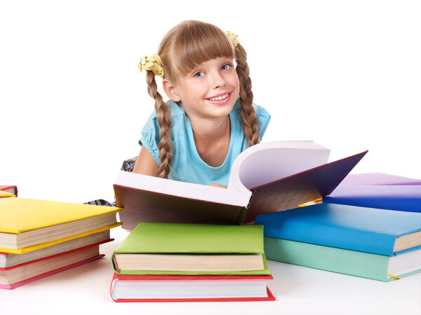 Child with pile of books reading on floor.