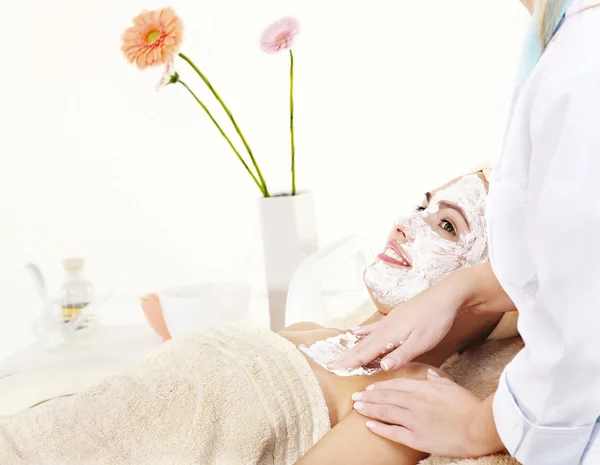 Kosmetikerin trägt Gesichtsmaske von Frau auf. — Stockfoto