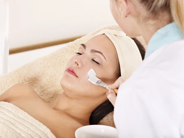 Kosmetikerin trägt Gesichtsmaske von Frau auf. — Stockfoto