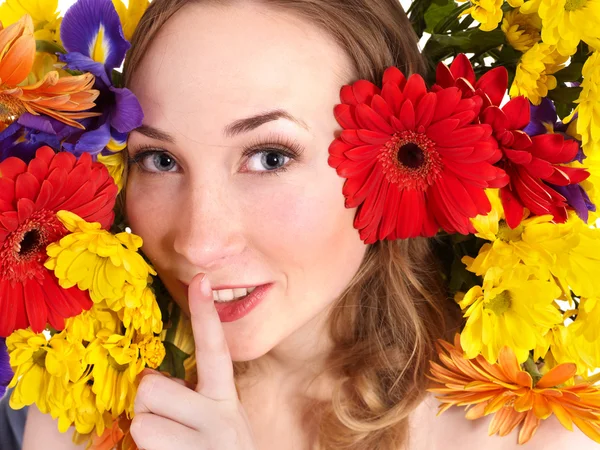 Young woman in flowers making silence gesture.