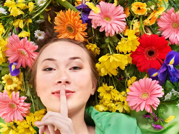 Young woman in flowers making silence gesture. — Stock Photo, Image