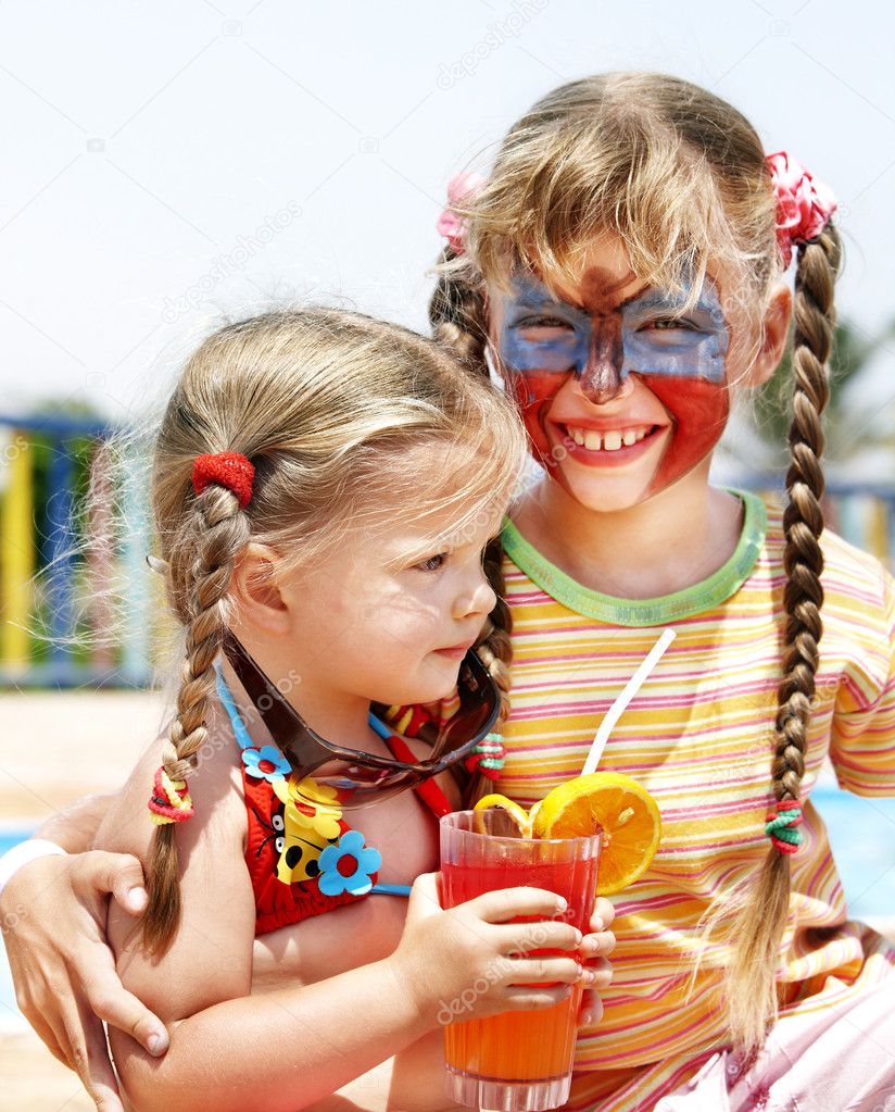 Children with face painting drinking juice.