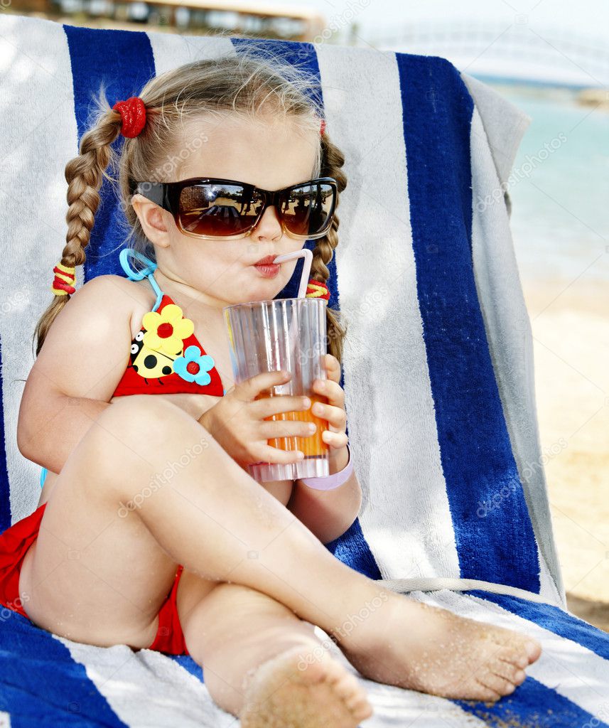 Child in glasses and red bikini drink juice.