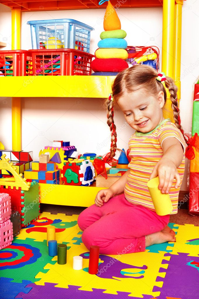 Child with puzzle, block and construction set in playroom.