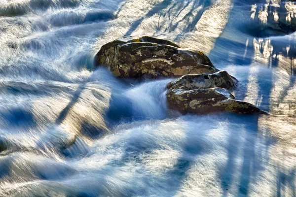 Szaleje przepływa rzeka wokół skały — Zdjęcie stockowe