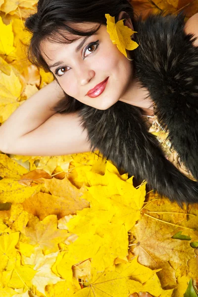Sonbahar yaprakları üzerinde yatan kız. — Stok fotoğraf